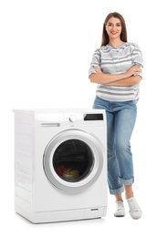 Photo of Young woman standing near washing machine with dirty laundry on white background