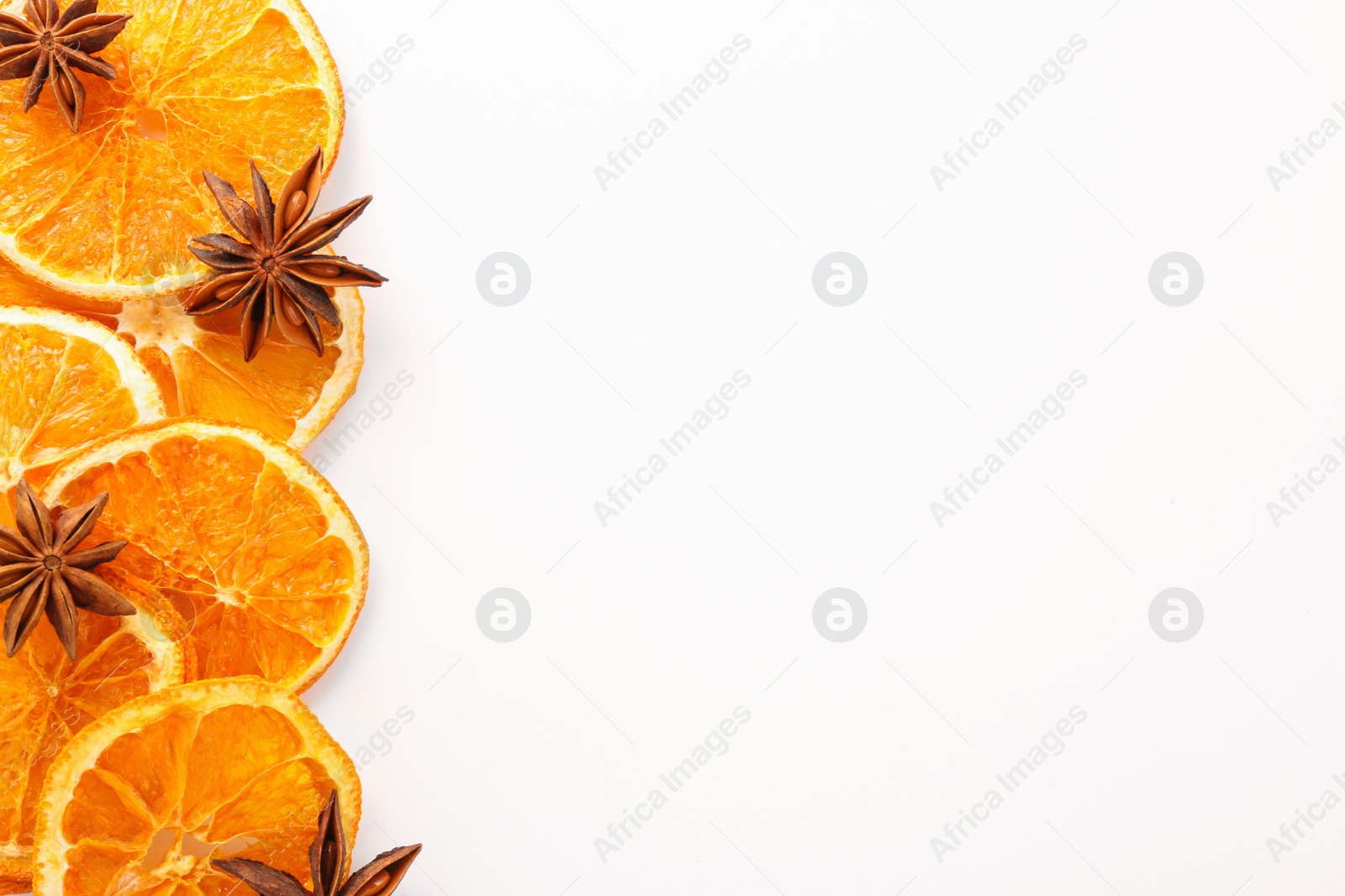 Photo of Dry orange slices and anise stars on white background, flat lay. Space for text