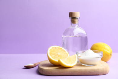 Photo of Baking soda, lemons and vinegar on lilac background. Space for text