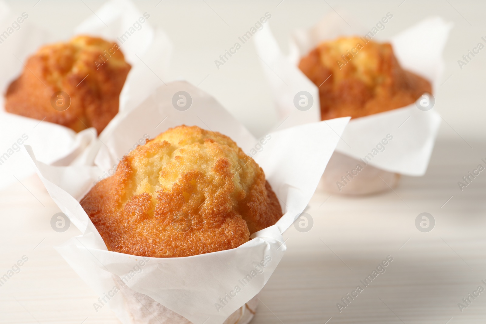 Photo of Tasty muffins on white wooden table, closeup. Fresh pastry