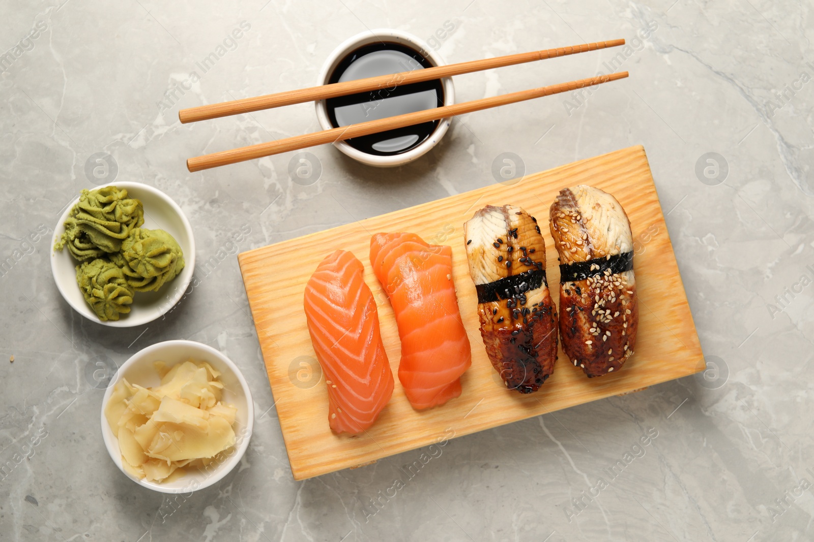 Photo of Delicious nigiri sushi, soy sauce, wasabi, ginger and chopsticks on light grey marble table, flat lay