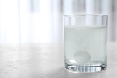 Photo of Glass of water with effervescent tablet on light table indoors, space for text