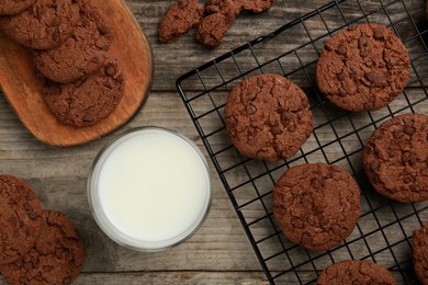 Photo of Delicious chocolate chip cookies and glass of milk on wooden table, flat lay