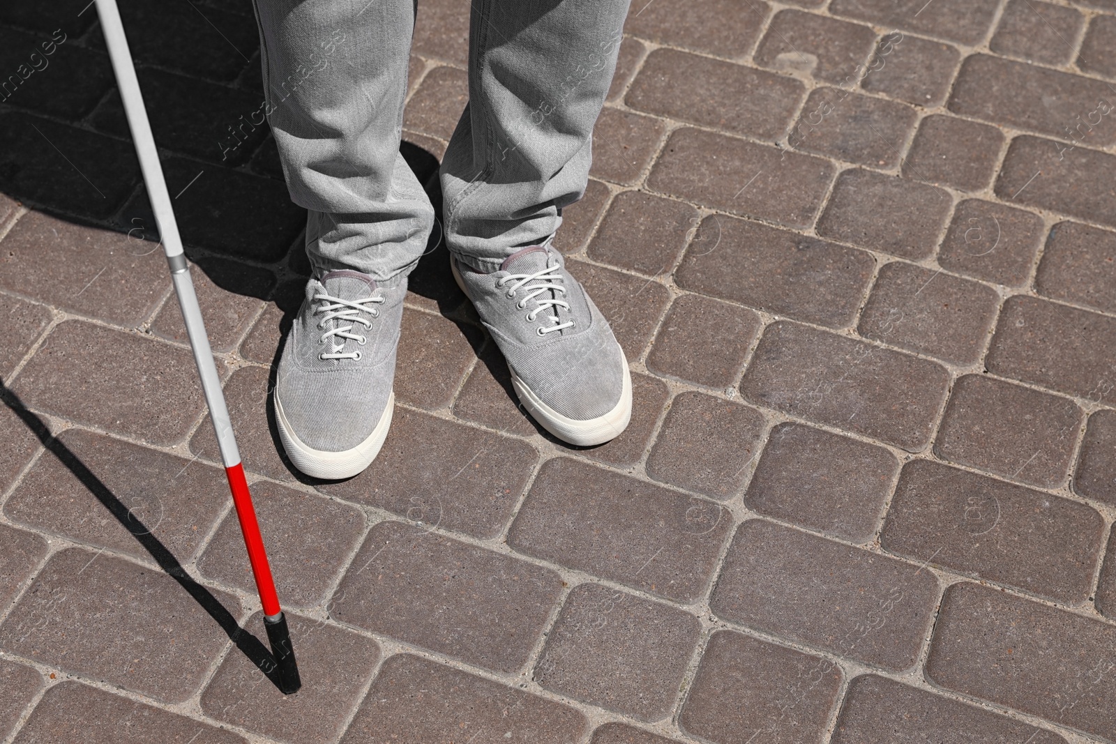 Photo of Blind person with cane walking outdoors, closeup. Space for text