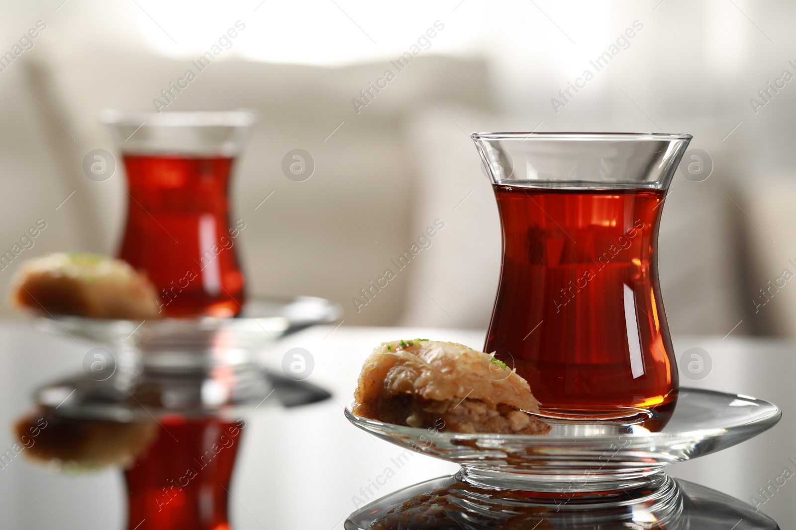 Photo of Glass of traditional Turkish tea and delicious baklava on table indoors, space for text