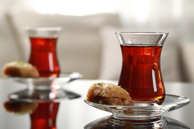 Photo of Glass of traditional Turkish tea and delicious baklava on table indoors, space for text