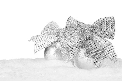 Photo of Beautiful silver Christmas balls with bows on snow against white background