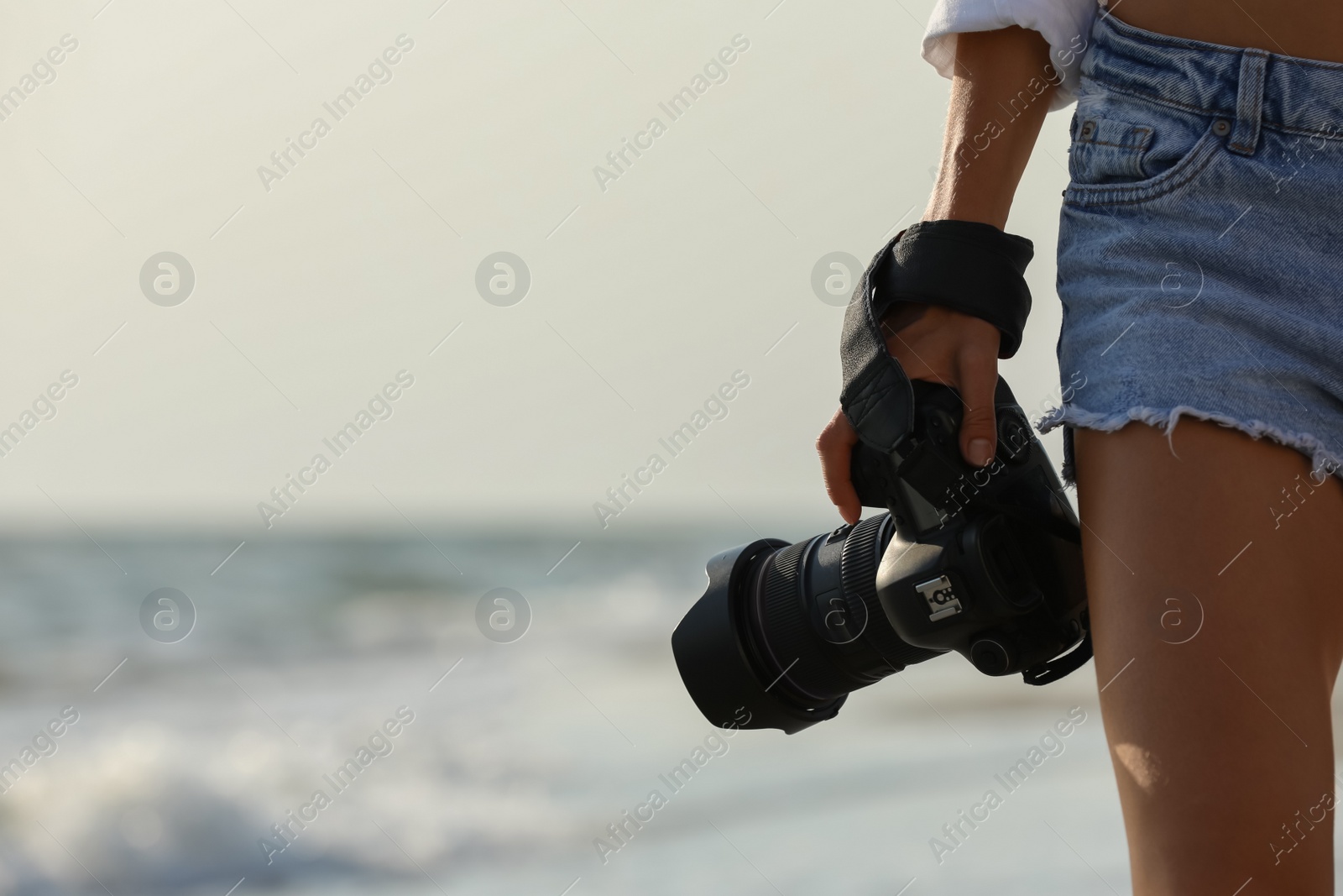 Photo of Photographer with professional camera near sea, closeup