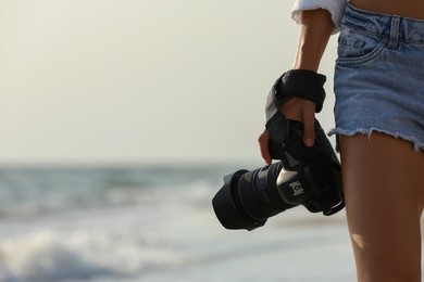 Photo of Photographer with professional camera near sea, closeup