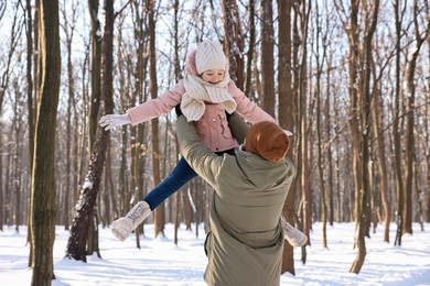 Photo of Family time. Father playing with his daughter in snowy forest, back view