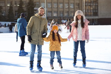 Image of Happy family spending time together at outdoor ice skating rink