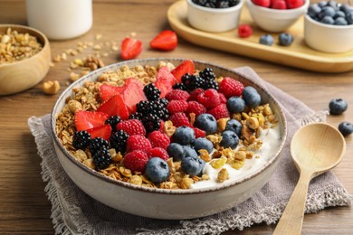 Photo of Healthy muesli served with berries on wooden table