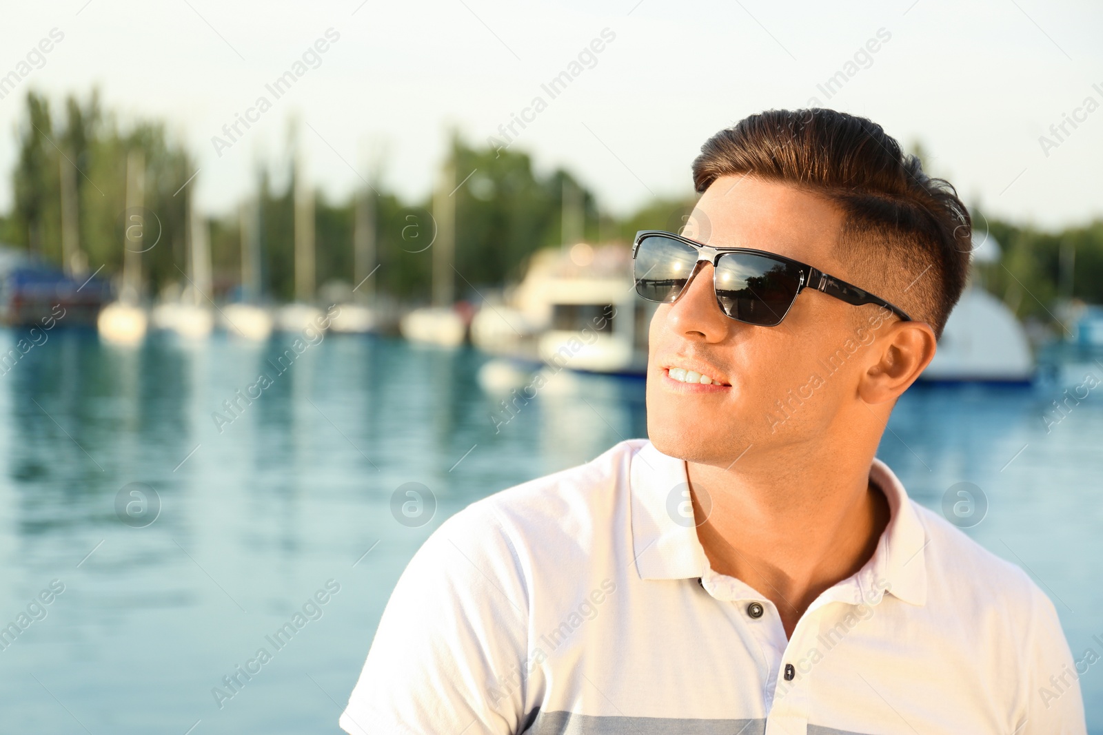 Photo of Handsome man wearing stylish sunglasses near river. Space for text