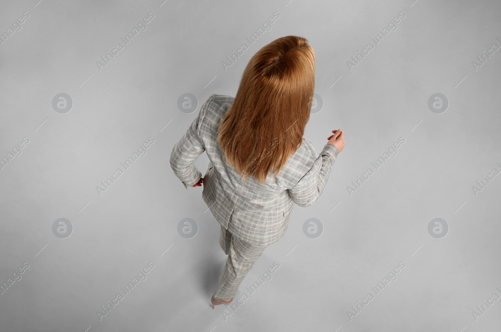 Photo of Young woman on grey background, back view