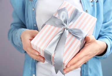 Photo of Young woman holding beautifully decorated gift box, closeup