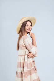 Young woman wearing stylish dress on light grey background