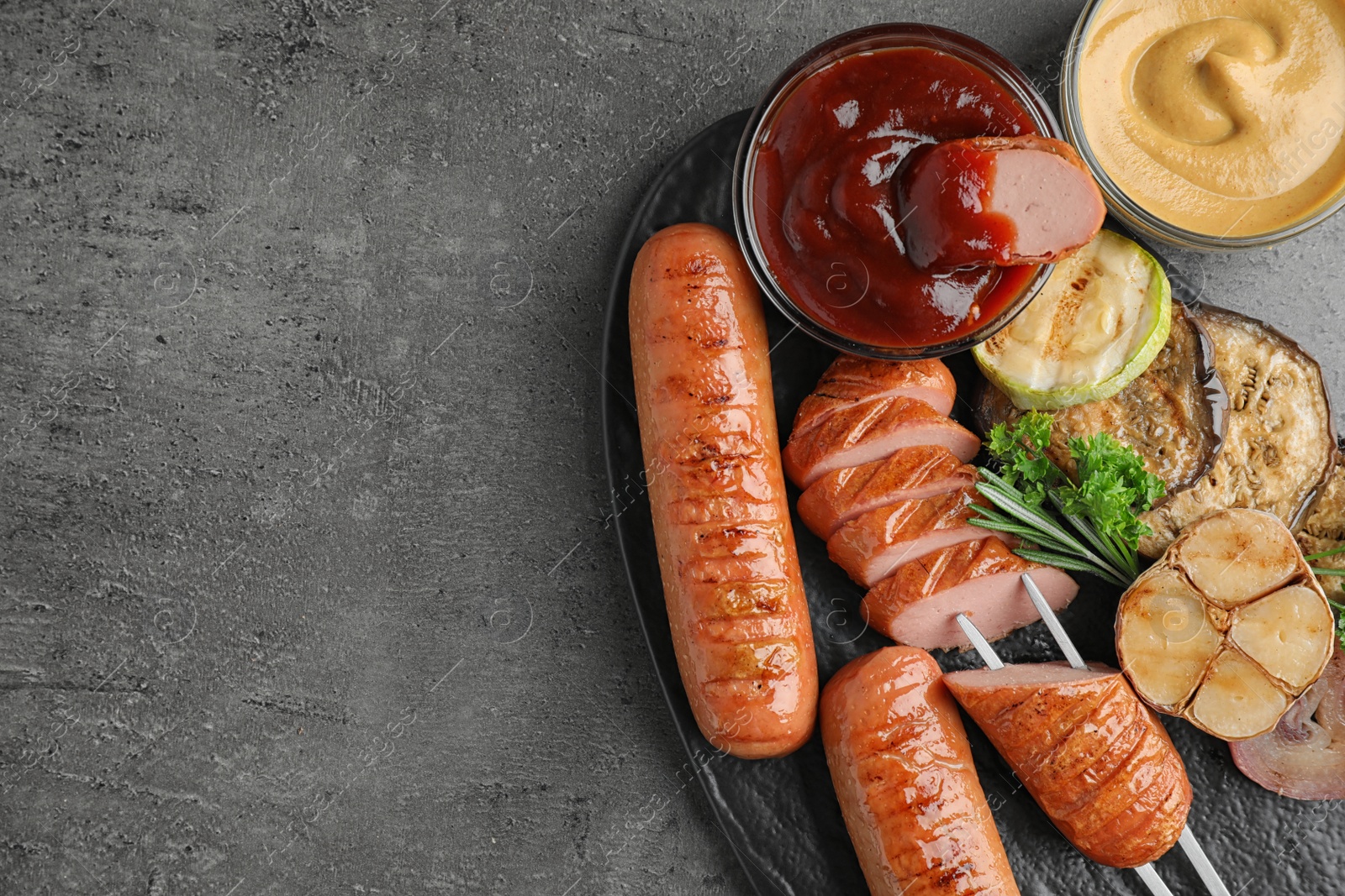 Photo of Delicious grilled sausages and vegetables on grey table, flat lay. Space for text