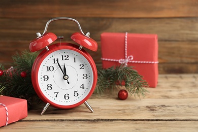 Beautiful composition with alarm clock and Christmas gifts on wooden table, space for text. Boxing day