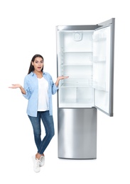 Photo of Emotional woman near empty refrigerator on white background