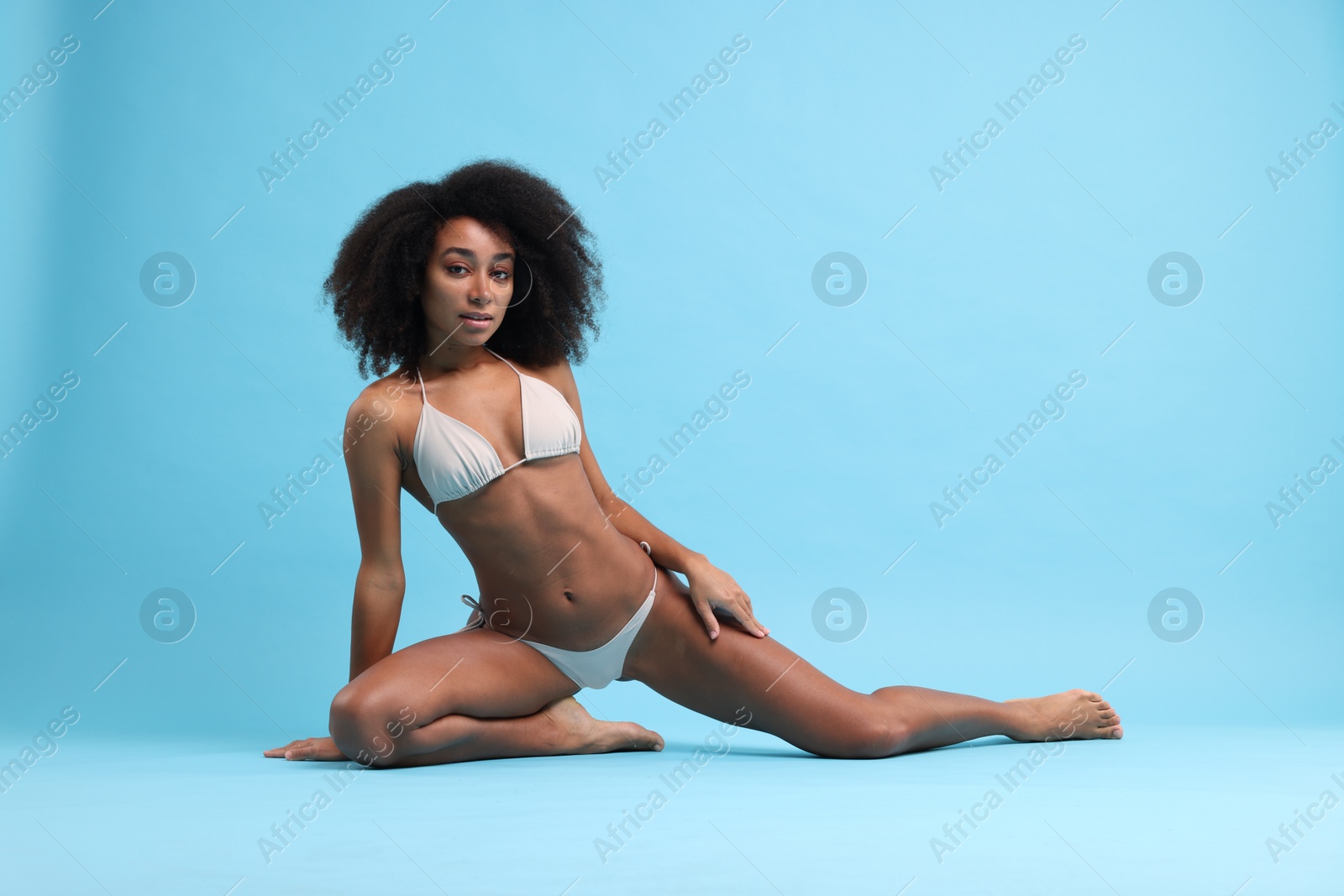 Photo of Beautiful woman in stylish bikini posing on light blue background