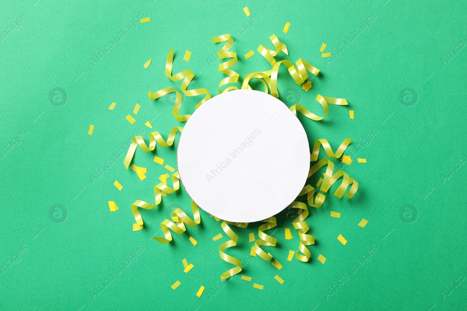 Photo of Blank card, yellow serpentine streamers and confetti on green background, flat lay. Space for text