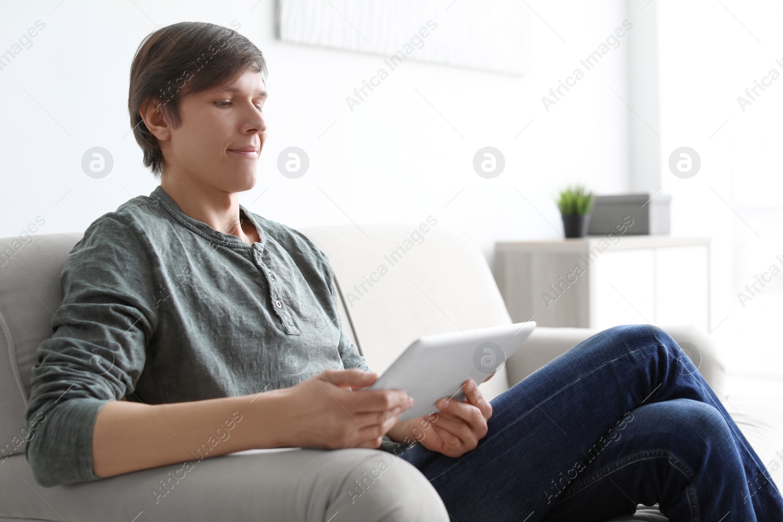 Photo of Portrait of young man with tablet on sofa