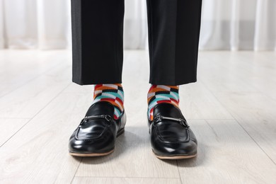 Photo of Man in stylish colorful socks, shoes and pants indoors, closeup