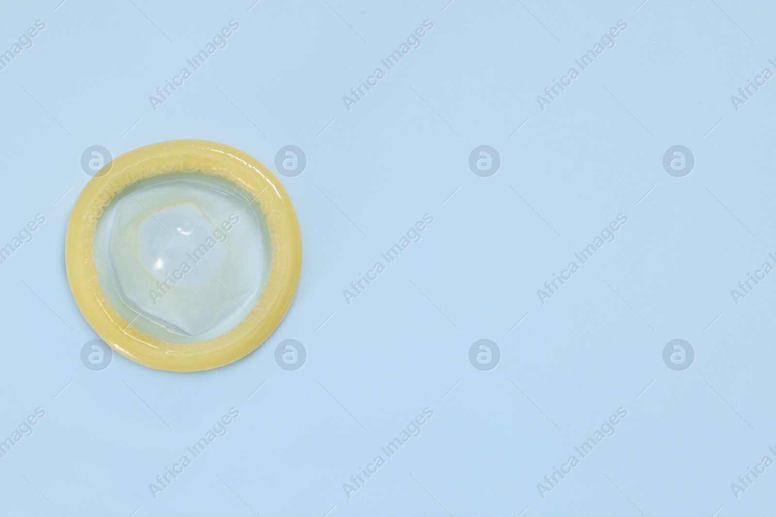 Photo of Condom on light blue background, top view with space for text. Safe sex