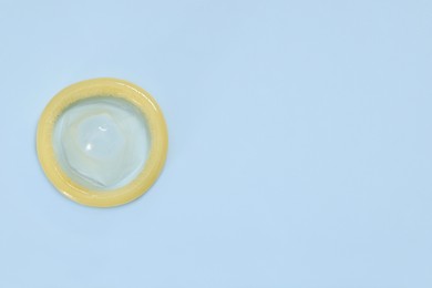 Condom on light blue background, top view with space for text. Safe sex