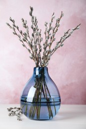 Photo of Beautiful bouquet of pussy willow branches in vase on white wooden table