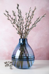 Beautiful bouquet of pussy willow branches in vase on white wooden table