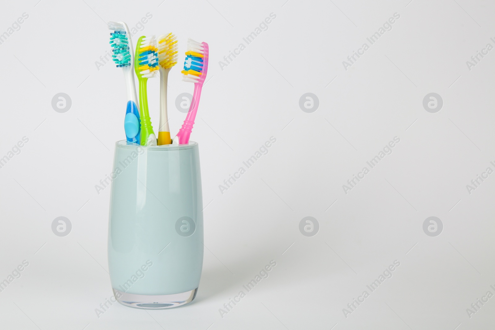 Photo of Different toothbrushes in holder on light grey background. Space for text