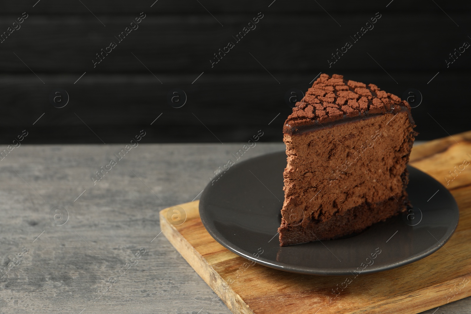 Photo of Piece of delicious chocolate truffle cake on grey textured table, space for text