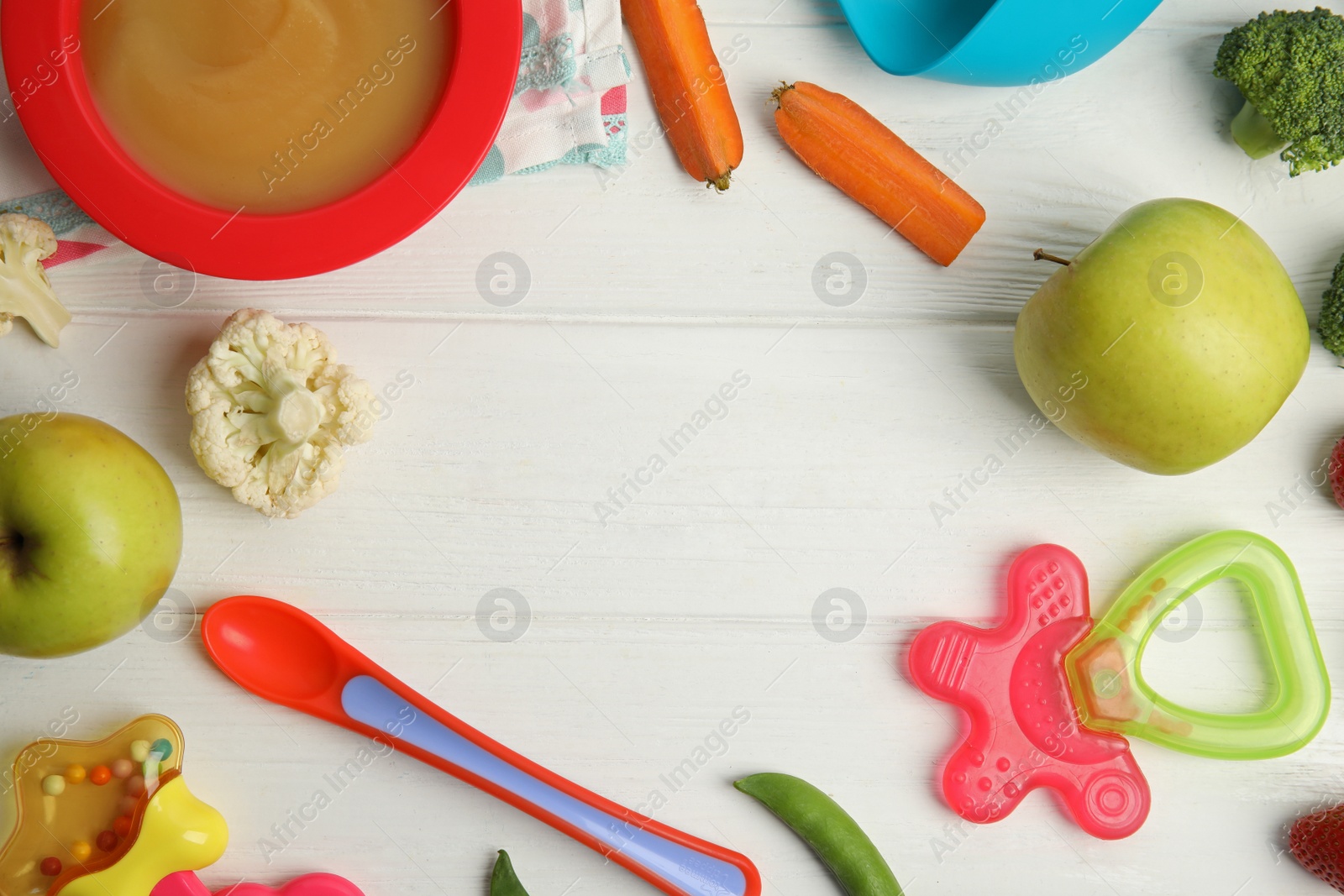 Photo of Frame of healthy baby food, ingredients and accessories on white wooden table, flat lay. Space for text