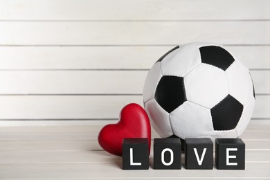 Photo of Soccer ball, heart and cubes with word Love on white wooden table. Space for text