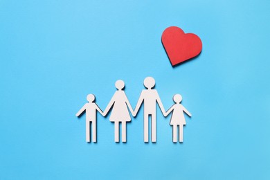 Photo of Figures of family and heart on light blue background, flat lay. Insurance concept