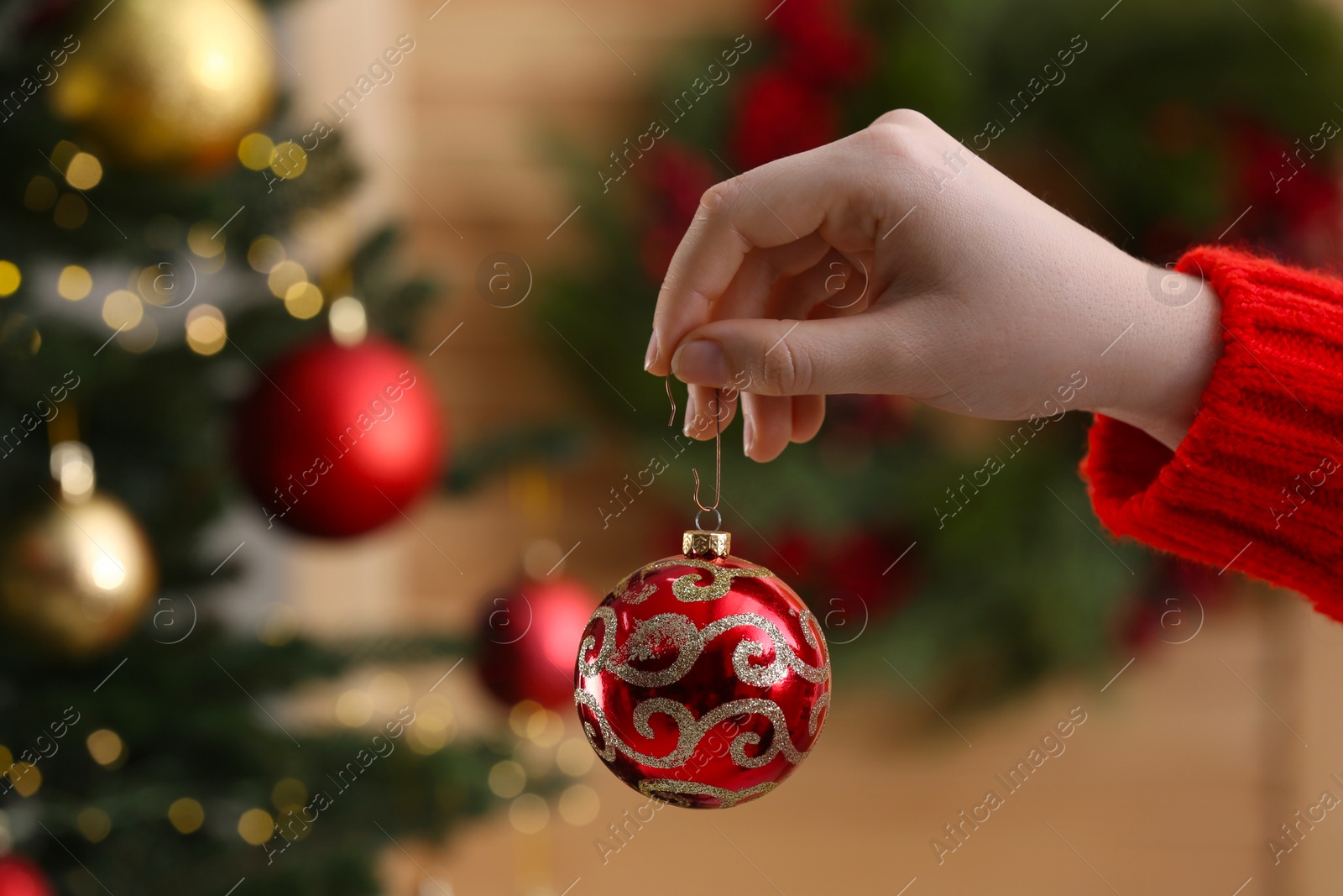 Photo of Woman holding red ball near Christmas tree indoors, closeup