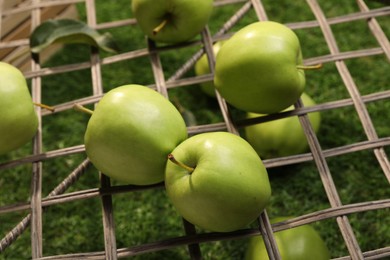 Photo of Many fresh green apples on rattan grid