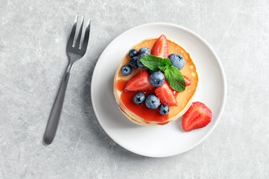 Plate with pancakes and berries on grey background, top view