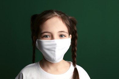 Photo of Girl wearing protective mask on green background Child's safety from virus