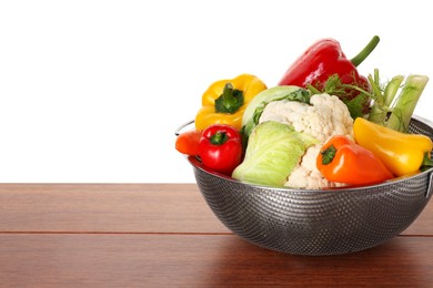 Photo of Metal colander with different vegetables on wooden table against white background, space for text