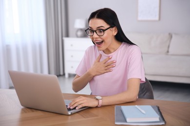 Emotional woman participating in online auction using laptop at home