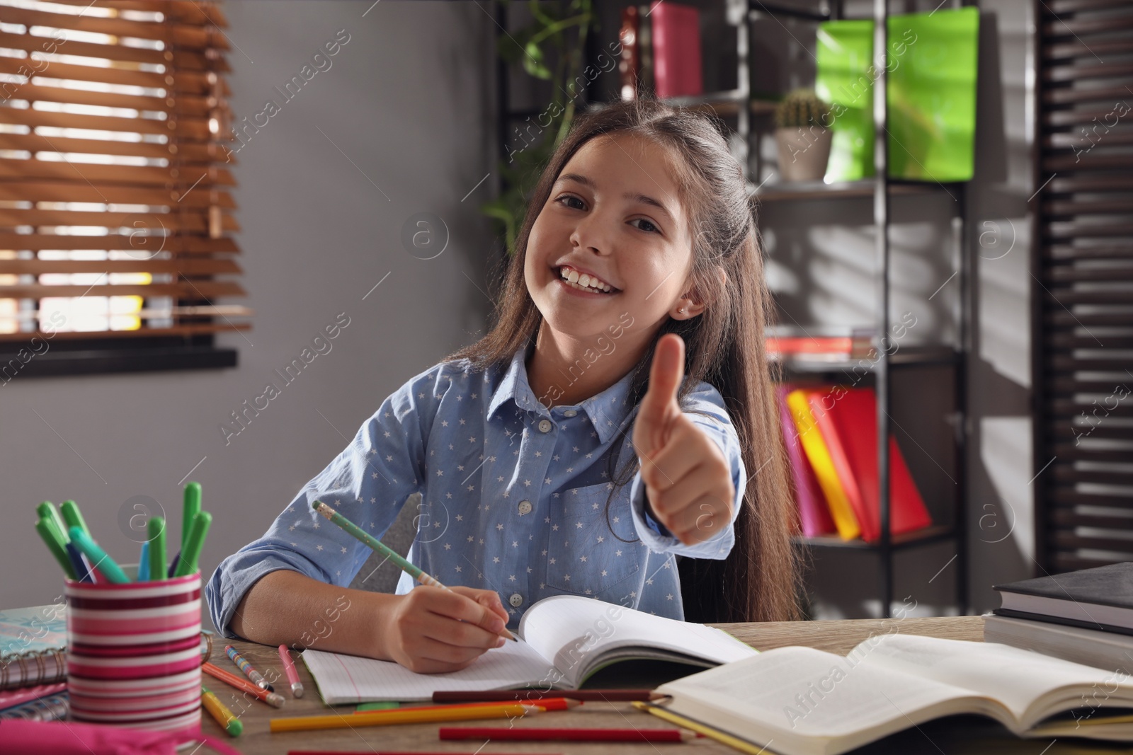 Photo of Pretty preteen girl doing homework at table