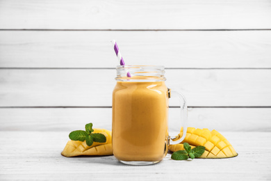 Fresh delicious mango drink on white wooden table