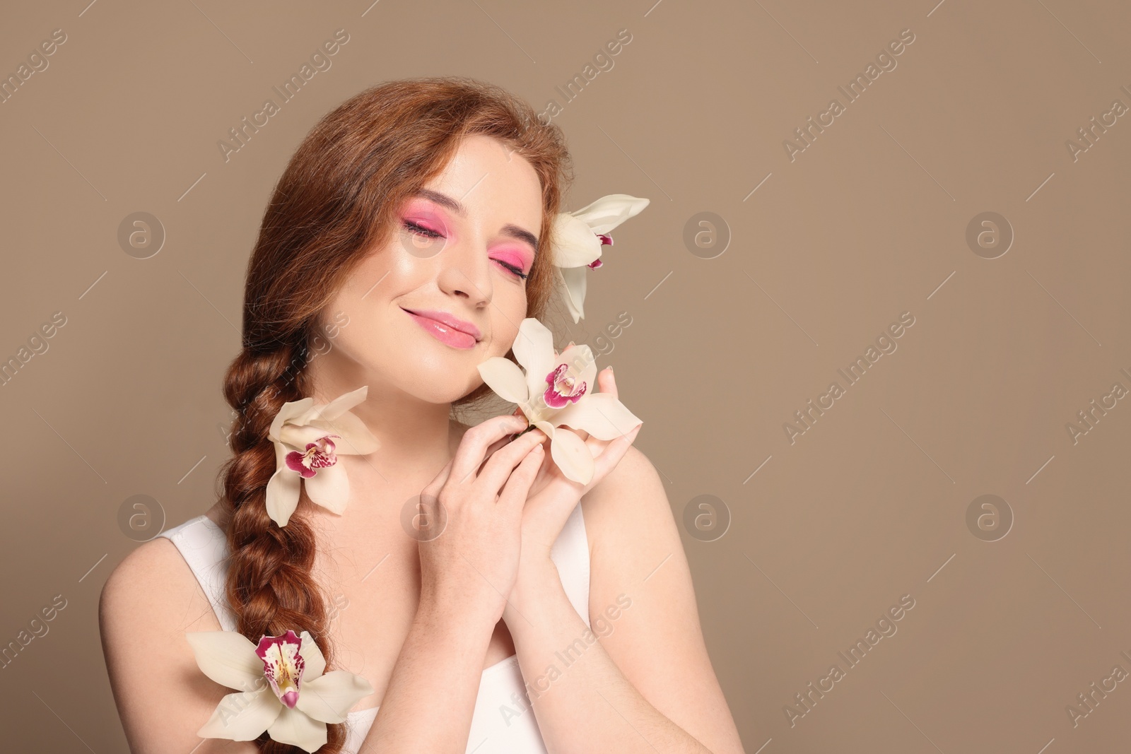 Photo of Portrait of beautiful happy woman posing with lilies on beige background. Space for text