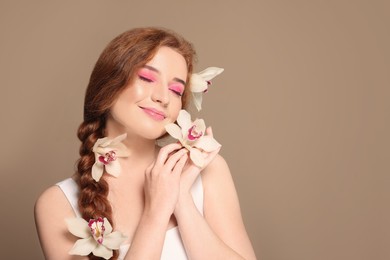 Portrait of beautiful happy woman posing with lilies on beige background. Space for text