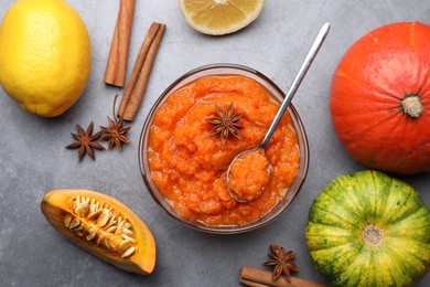 Bowl of delicious pumpkin jam and ingredients on grey table, flat lay