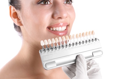 Photo of Dentist checking young woman's teeth color on white background, closeup