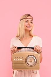 Portrait of happy hippie woman with retro radio receiver on pink background