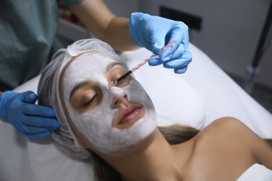 Photo of Cosmetologist applying mask on client's face in spa salon